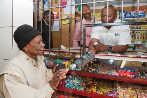 South African woman makes a purchase with her SASSA MasterCard Debit card at a local shop